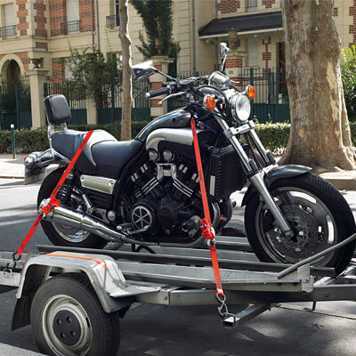 Motorcycle on trailer secured by a tie down strap Motorcycle on trailer secured by a tie down strap